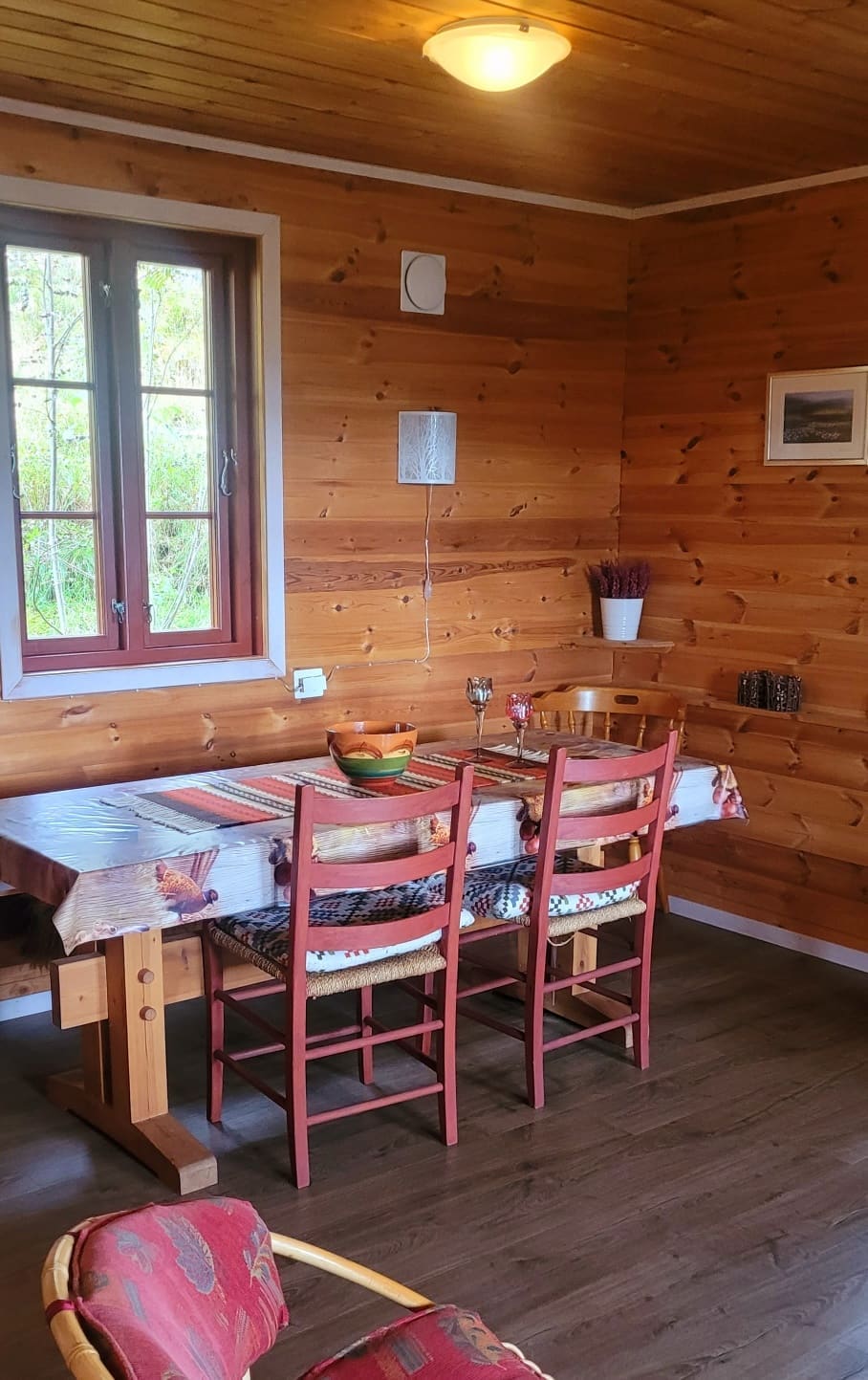 Spiseplass i Hytte 2 med langbord, raude stolar og panelvegger