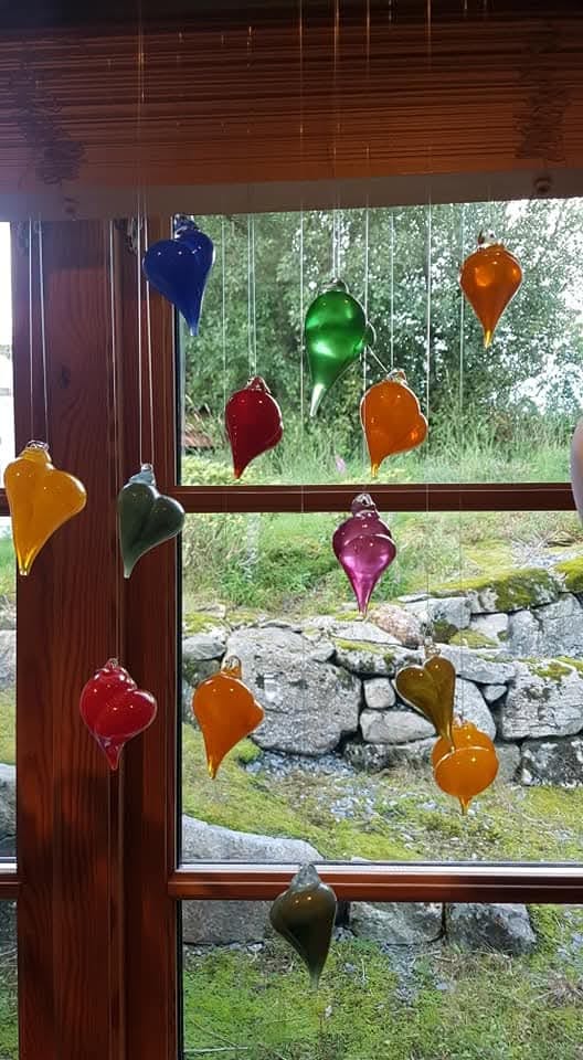 Glashjarte i mange fargar som heng i vindauget
